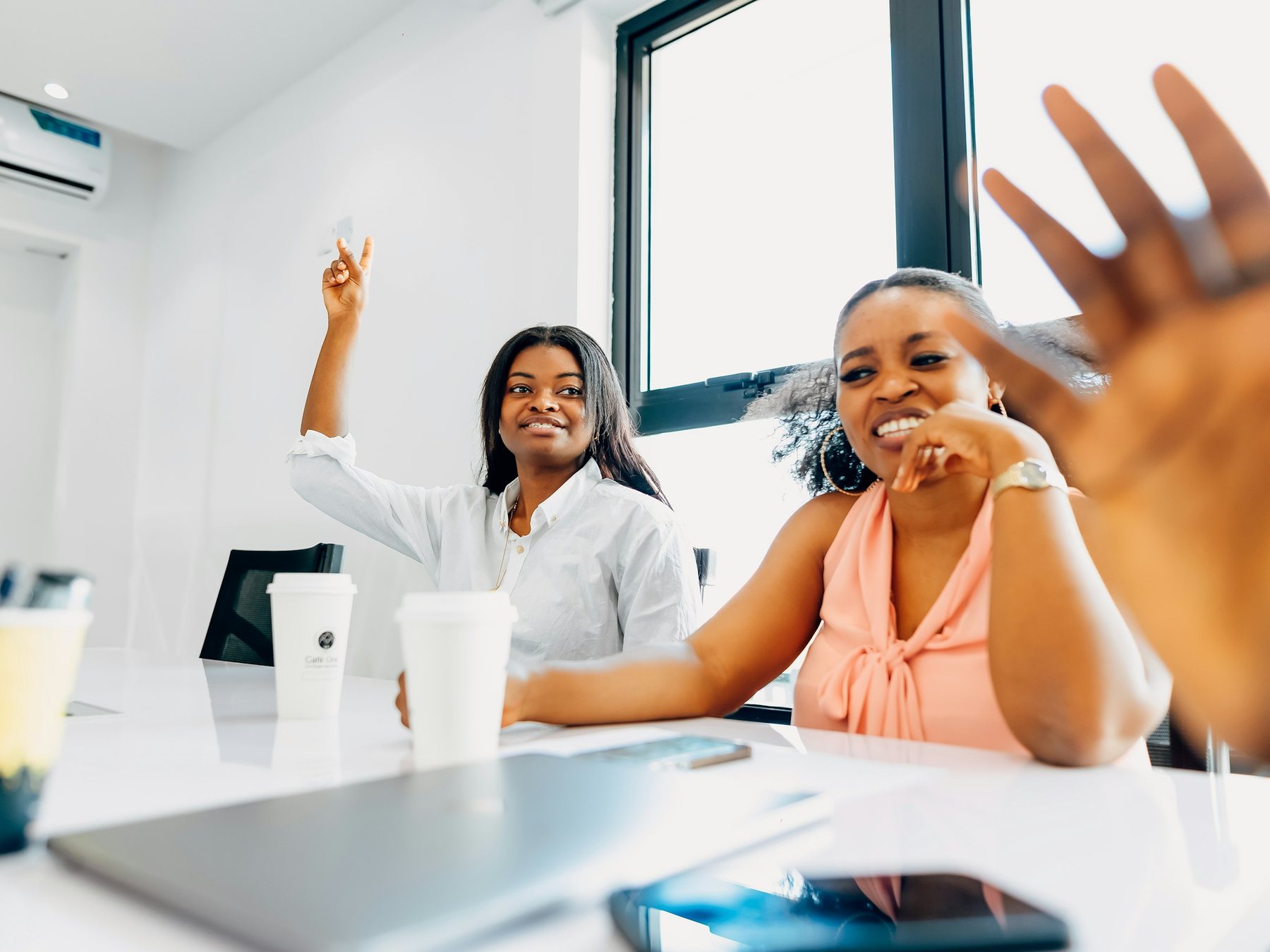 Échange chaleureux entre collaboratrices dans un bureau lumineux